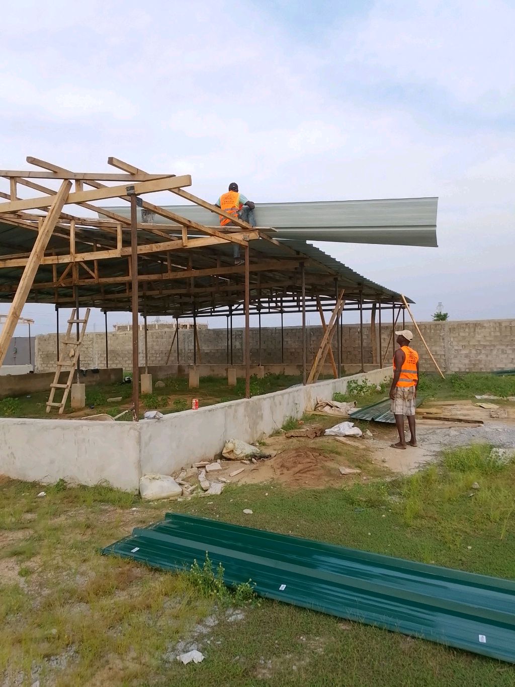 Ouvriers installant des tôles de toiture sur la charpente en bois d'un bâtiment