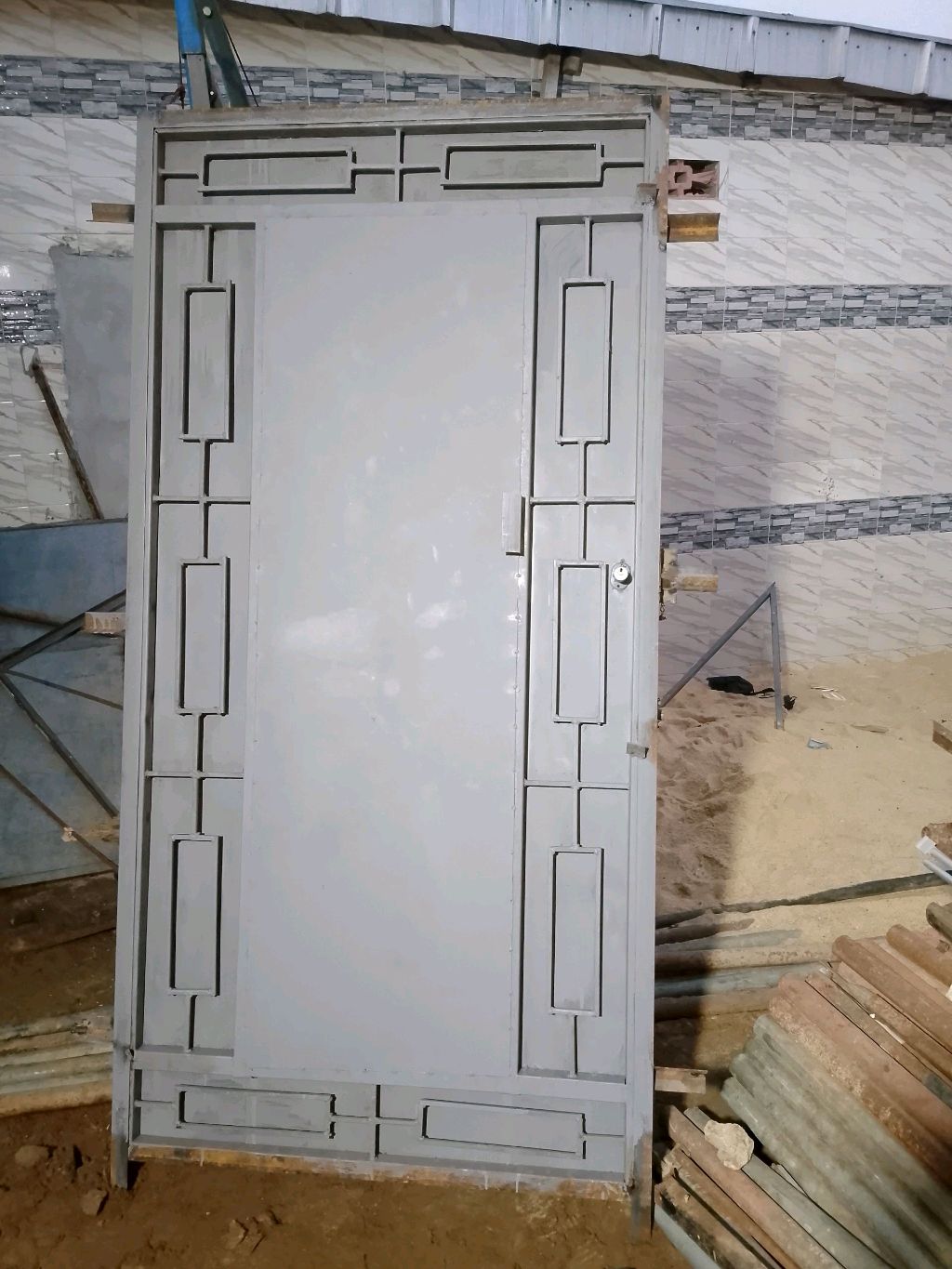Porte métallique grise décorée prête à être posée sur un chantier de bâtiment